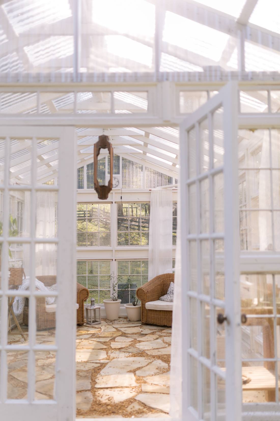 Looking in through the open French doors at wicker chairs, linen curtains and a flagstone floor